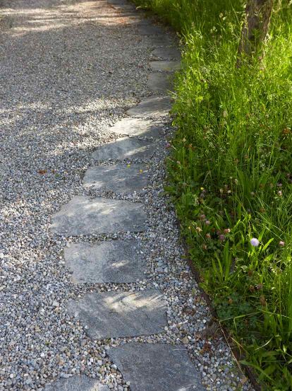 Schrittplatten aus Gneis führen durch Rundkies-Platz